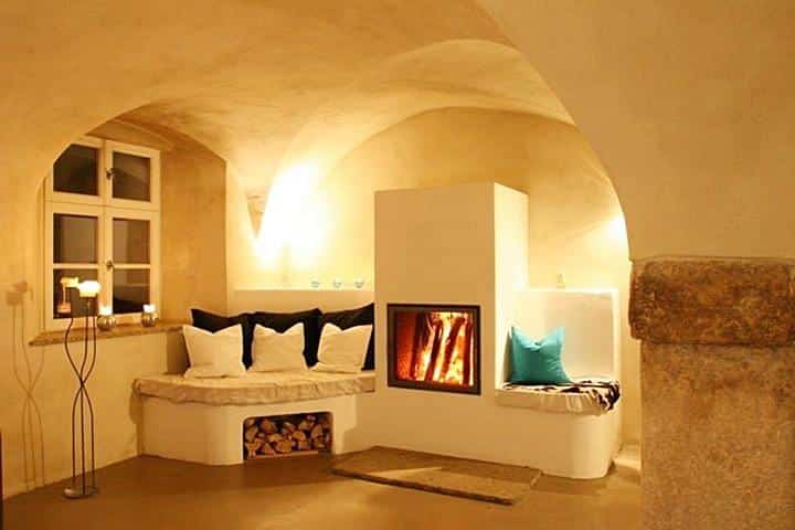 Gemütlicher, traditioneller Kamin mit Sitzbank von ambio im historischen Gewölberaum