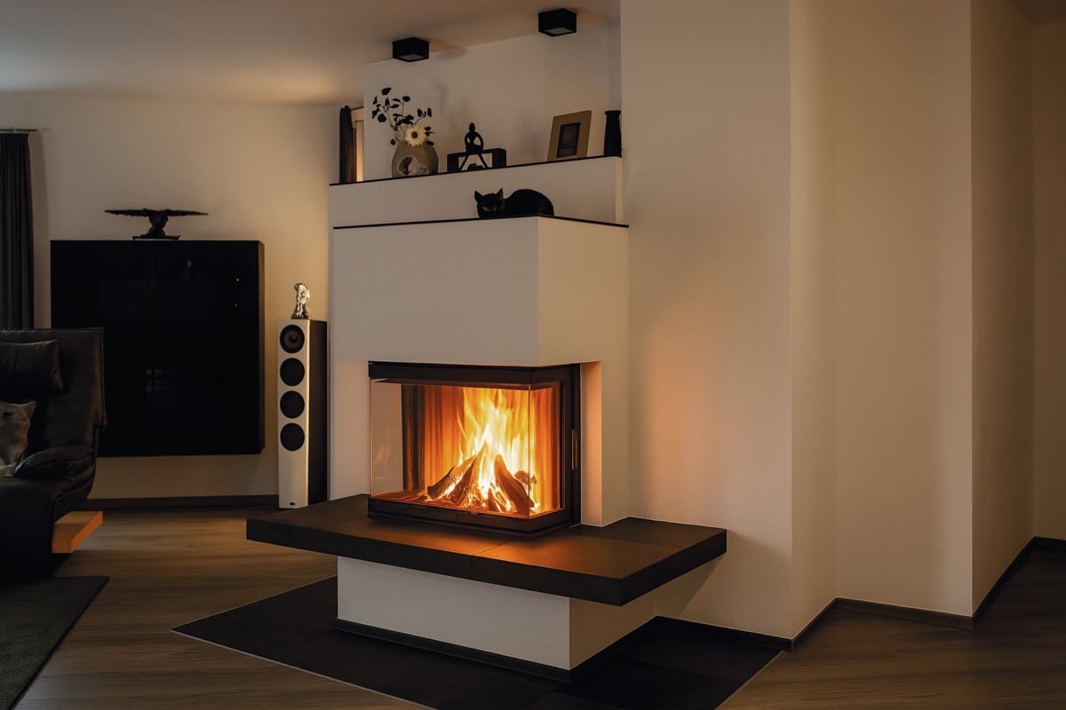 Moderner Eck-Speicherofen mit großer dreiseitiger Glasscheibe in gemütlichem Wohnzimmer mit dunklen Akzenten.